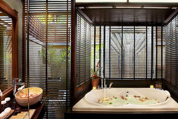 Ein Badezimmer mit Jacuzzi im Nora Buri Resort & Spa, umgeben von Pflanzen und mit offenen Jalousien.