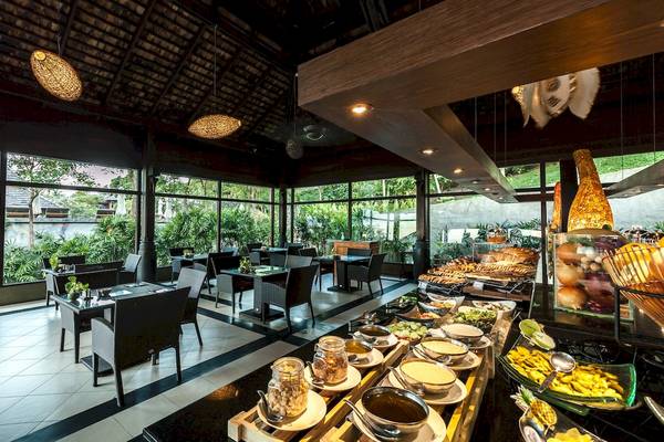 Innenansicht des Restaurants im Nora Buri Resort & Spa mit Tischen, Stühlen und Buffet.