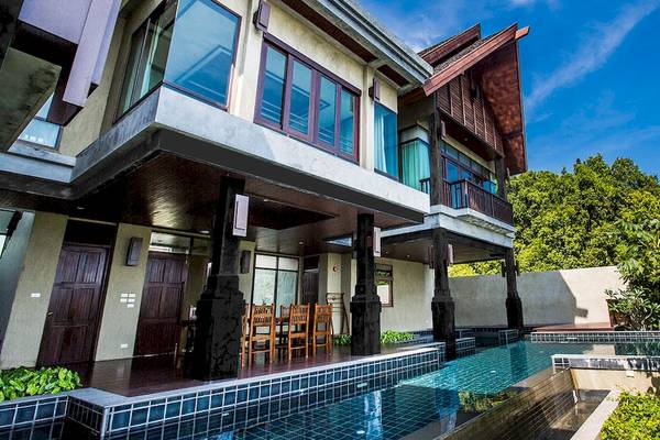 Außenansicht des Nora Buri Resort & Spa mit Pool und Terrassenmöbeln.