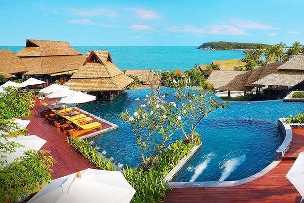 Außenansicht des Nora Buri Resorts & Spa mit großem Pool, Sonnenschirmen und Blick auf das Meer