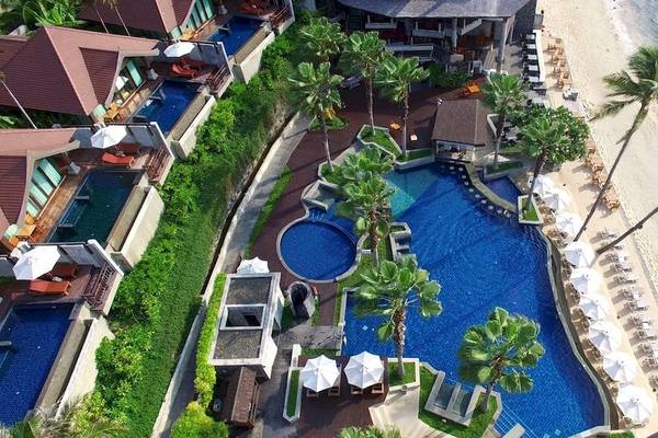 Luftaufnahme des Nora Buri Resorts und Spa mit Swimmingpool, Strand und Sonnenliegen.