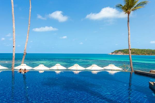 Außenpool mit Sonnenschirmen und Blick auf das Meer am Nora Buri Resort & Spa.