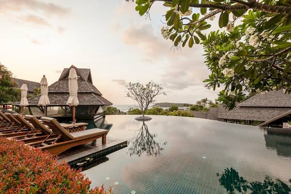 Außenpool des Nora Buri Resort & Spa mit Liegestühlen und Blick auf das Meer
