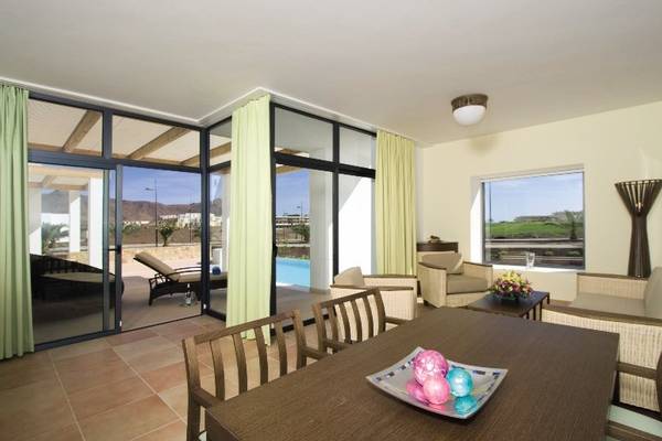 Playitas Hotel Innenbereich Wohnzimmer mit Poolblick und großen Fenstern.