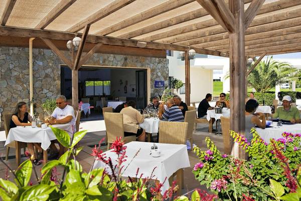 Gäste sitzen im Freien im Restaurant des Playitas Hotels und genießen ihr Essen.