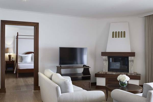 Innenansicht der Suite im Creta Maris Resort mit Wohnzimmer, Kamin und Fernseher.