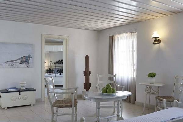 Innenansicht eines Zimmers im Creta Maris Resort mit weißen Möbeln, einem Tisch mit Äpfeln und einem Bett im Hintergrund.