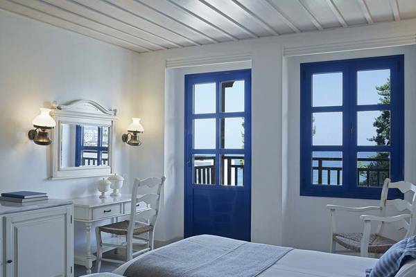 Innenansicht eines Zimmers im Creta Maris Resort mit zwei Betten, einem Schreibtisch, einem Spiegel und einer Aussicht auf das Meer.
