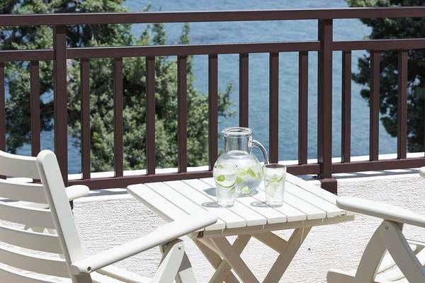 Balkon des Creta Maris Resorts mit Meerblick, zwei Stühle und ein Tisch mit Wasserkaraffe und Gläsern.