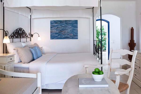 Schlafzimmer im Creta Maris Resort mit Himmelbett, weißem Bettlaken, Kissen und Nachttisch.