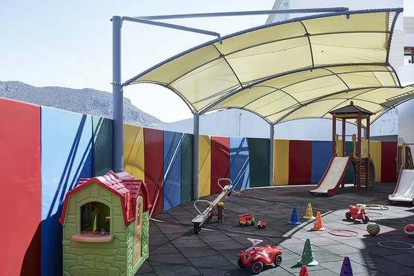 Kinderspielplatz im Creta Maris Resort mit Rutsche, Spielhaus und bunten Wänden.