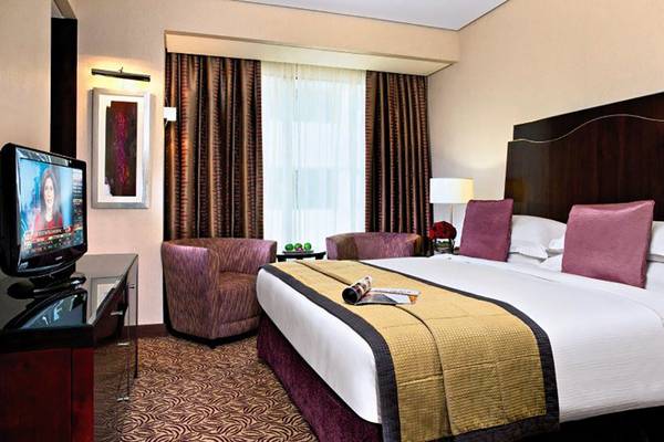 Rose Rayhaan by Rotana Hotelzimmer mit Fernseher, Bett, Sesseln und Dekor.