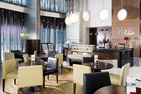 Innenansicht des Cafe Rose im Hotel Rose Rayhaan by Rotana mit gepolsterten Stühlen und Tischen.