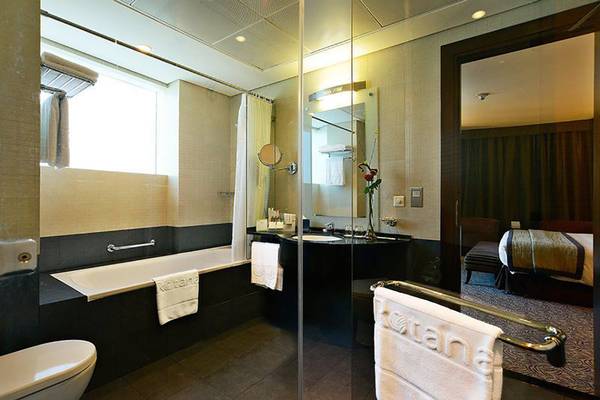Badezimmer im Rose Rayhaan by Rotana Hotel mit Badewanne, Waschbecken und Spiegel.