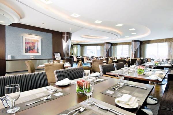 Innenansicht des Restaurants im Rose Rayhaan Hotel mit gedeckten Tischen und modernen Möbeln.