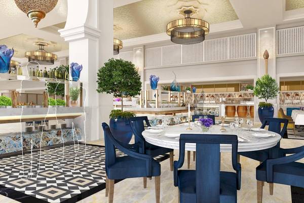 Innenbereich des Rixos Premium Saadiyat Island Hotels mit blauen Stühlen und Tisch, Pflanzen und Kronleuchtern.