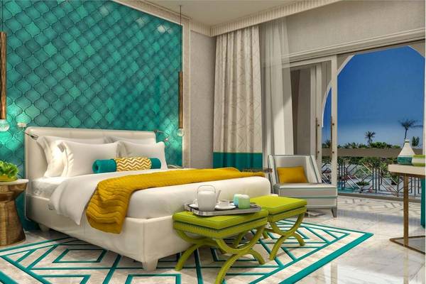 Luxuriöses Hotelzimmer im Rixos Premium Saadiyat Island mit türkisfarbener Wand, weißem Bett und grünen Hockern.
