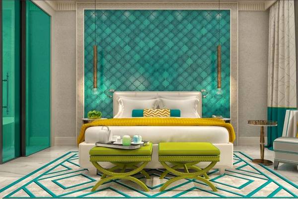 Schlafzimmer im Rixos Premium Saadiyat Island Hotel mit türkisfarbener Wand und grünen Akzenten.