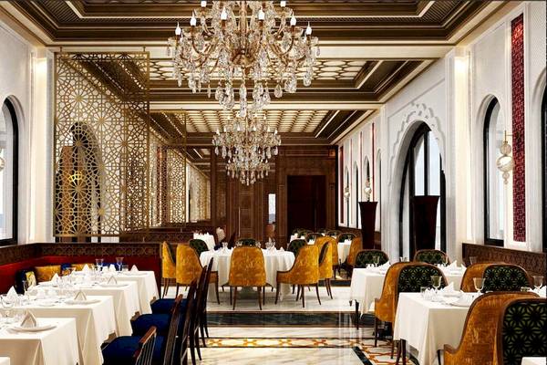 Innenbereich des Restaurants im Rixos Premium Saadiyat Island Hotel mit goldenen Kronleuchtern und eleganten Esstischen.