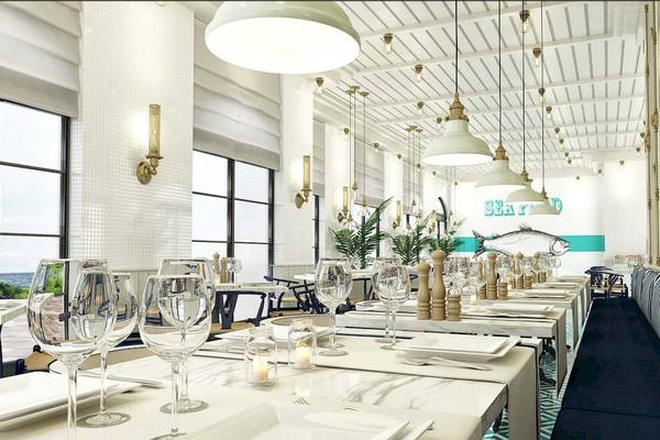 Innenansicht des Rixos Premium Saadiyat Island Restaurants mit Tisch, Gläsern und Meeresdekor.