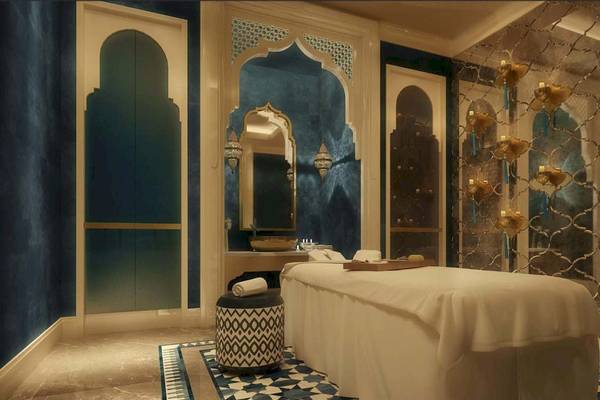 Spa-Behandlungsraum im Rixos Premium Saadiyat Island mit weißem Bett, blauen Wänden und goldenen Leuchten.