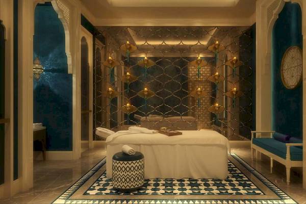 Spa-Behandlungsraum im Rixos Premium Saadiyat Island Hotel mit weißem Behandlungsbett, blauen Wänden und Marmorboden.
