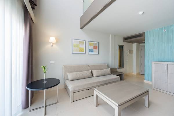 Inneneinrichtung des HD Beach Resort Zimmers mit Sofa, Tischen und Gemälden an der Wand.