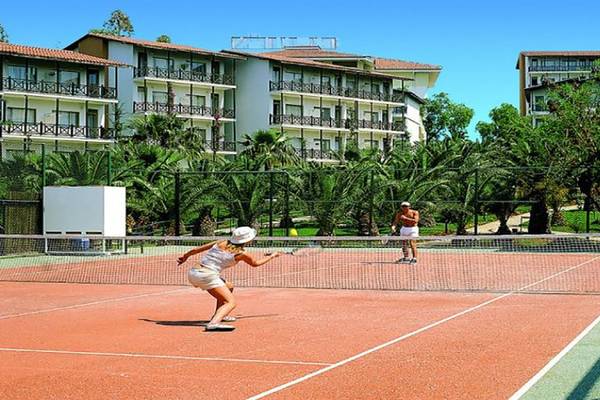 Tennisplatz im Sealife Buket Resort & Spa mit zwei Spielern und einem Gebäude im Hintergrund.