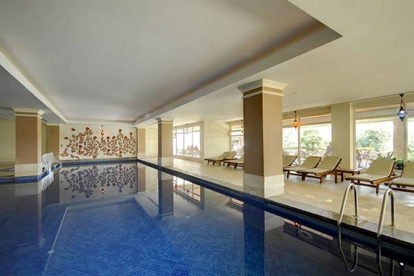 Innenpool des Sealife Buket Resort & Spa mit Sonnenliegen und Wandkunst.