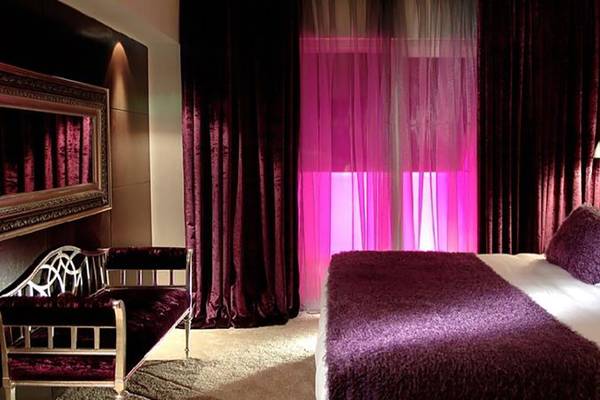 Schlafzimmer im Sealife Buket Resort & Spa mit violetten Vorhängen und pinkem Licht.