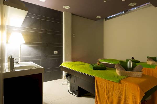Massageraum im HD Beach Resort mit grünen und orangefarbenen Massageliegen und einem Waschbecken.