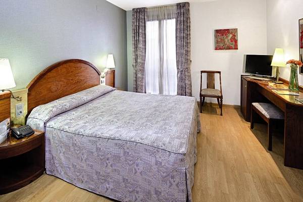Innenansicht eines Zimmers im Gargallo Rialto Hotel mit Bett, Schreibtisch und Fernseher.