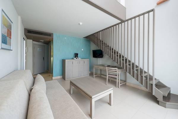 Inneneinrichtung einer Suite im HD Beach Resort mit Wohnzimmer, Couch, Tisch und Schreibtisch.