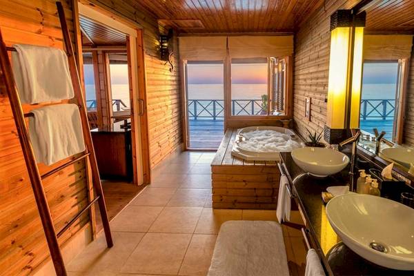 Ein Badezimmer im Komandoo Island Resort & Spa mit Badewanne, Spiegel und Meerblick.