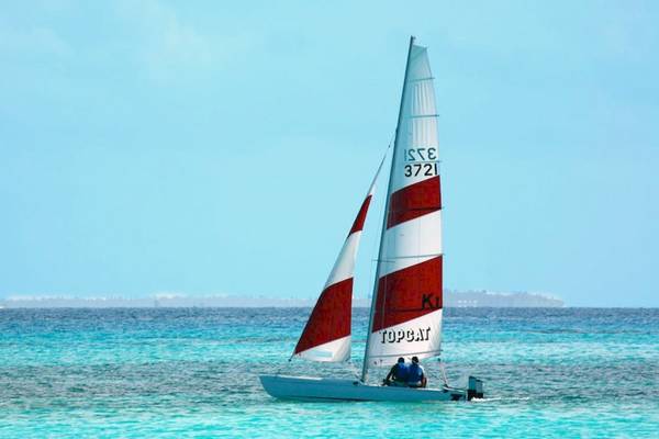 Ein rotes und weißes Segelboot fährt auf dem blauen Meer.