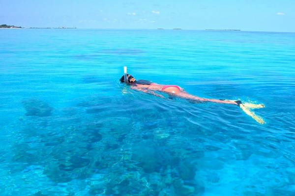 Eine Frau schwimmt im klaren Wasser der Komandoo Insel mit Schnorchel und Flossen.