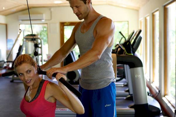 Ein Fitnesstrainer hilft einer Frau im Gym, Übungen durchzuführen.