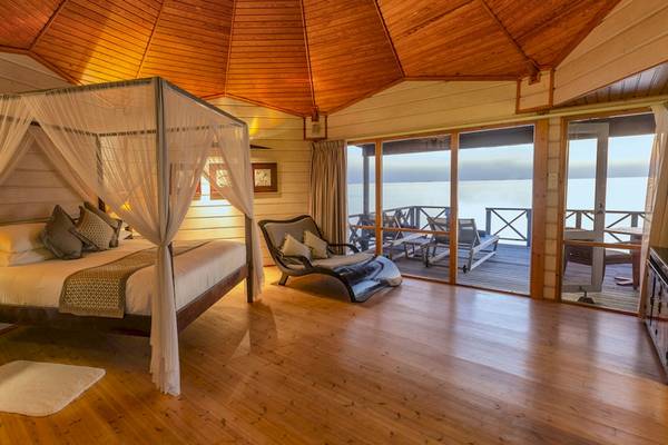 Schlafzimmer im Komandoo Island Resort & Spa mit Bett, Decken und Aussicht auf den Ozean.