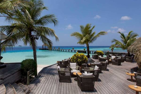 Außenterrasse des Komandoo Island Resorts & Spa mit Blick auf das Meer und Palmen.