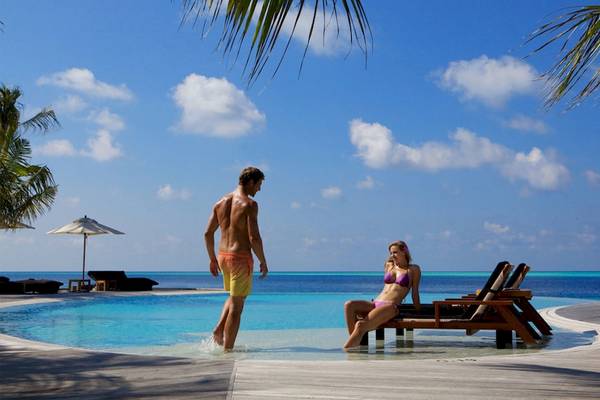 Ein Mann und eine Frau genießen den Poolbereich des Komandoo Island Resort & Spa.