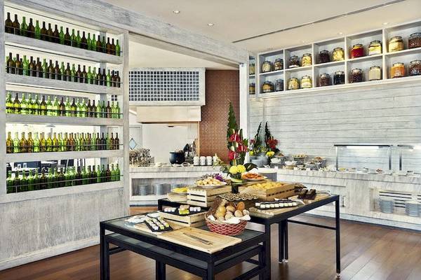 Speisesaal des Mövenpick Hotel Sukhumvit 15 Bangkok mit gedeckten Tischen, Flaschenwand und Holzboden.