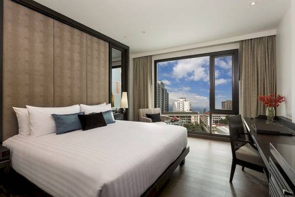 Schlafzimmer im Mövenpick Hotel Sukhumvit 15 Bangkok mit großem Bett und Ausblick auf die Stadt.
