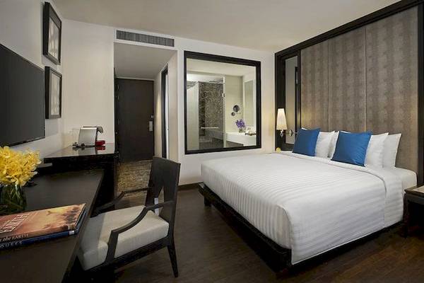 Zimmer im Mövenpick Hotel Sukhumvit 15 Bangkok mit Bett, Schreibtisch, Stuhl und Dekoration.