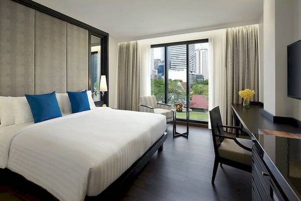 Innenansicht eines Schlafzimmers im Mövenpick Hotel Sukhumvit 15 Bangkok, mit einem großen Bett, Fenstern und Stadtblick.