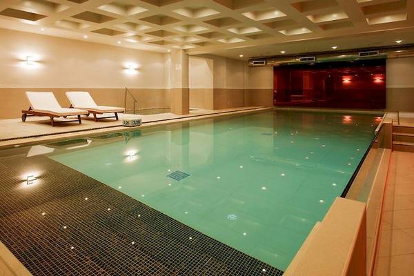 Innenpool des Sentido Pearl Beach Hotels mit zwei Sonnenliegen und beleuchtetem Becken.