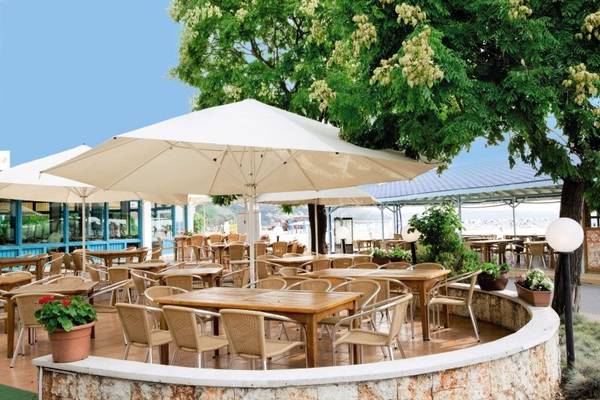 Außenterrasse des Kaliopa Hotels mit mehreren Tischen und Stühlen unter Sonnenschirmen.