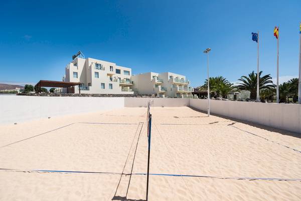 Volleyballplatz am HD Beach Resort mit weißen Gebäuden im Hintergrund und Palmen.