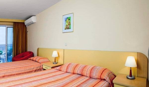 Doppelzimmer im Kaliopa Hotel mit Balkon und Meerblick, zwei Betten, Schreibtisch und Fernseher.