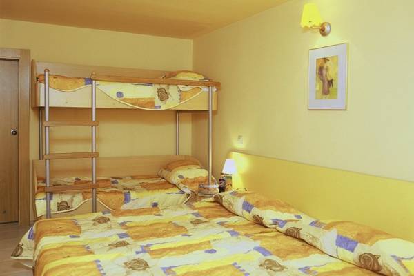 Schlafzimmer im Kaliopa Hotel mit Doppelstockbett und Einzelbett, gelben Wänden und Gemälde an der Wand.