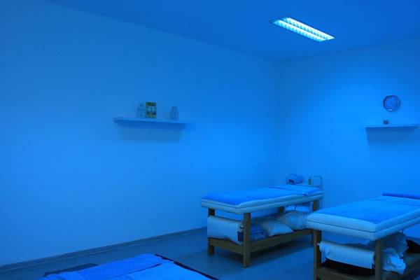 Massageraum im Callisto Holiday Village mit blauen Wänden und zwei Massagetischen.